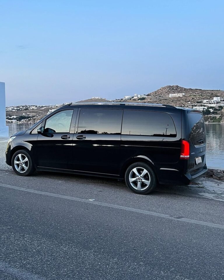A scenic landscape featuring rolling hills and a clear blue sky, with patches of green grass and scattered trees.